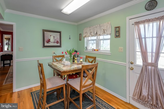 dining area featuring crown molding, wood finished floors, and baseboards