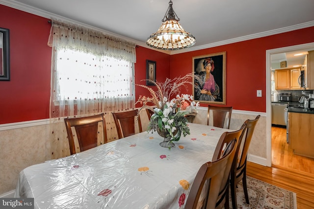 dining area featuring a wainscoted wall, wood finished floors, and ornamental molding