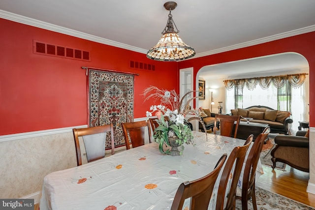 dining room featuring arched walkways, crown molding, and wood finished floors