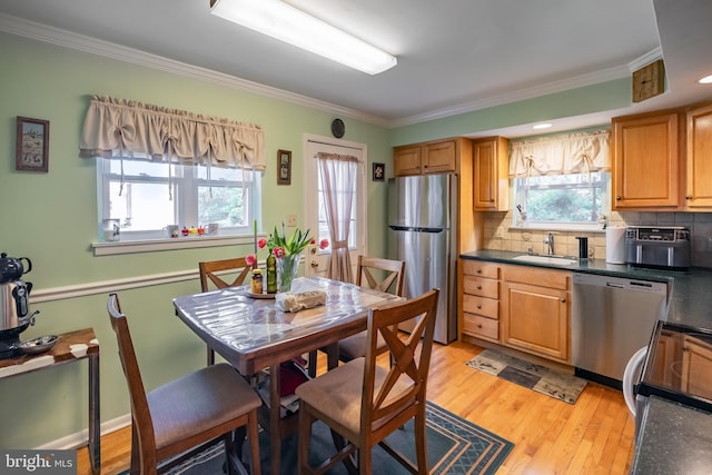 kitchen with appliances with stainless steel finishes, a sink, crown molding, dark countertops, and tasteful backsplash