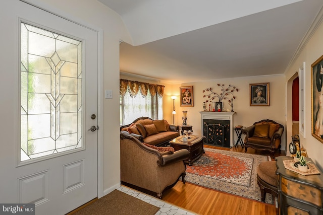 living room featuring arched walkways, a fireplace, wood finished floors, and ornamental molding