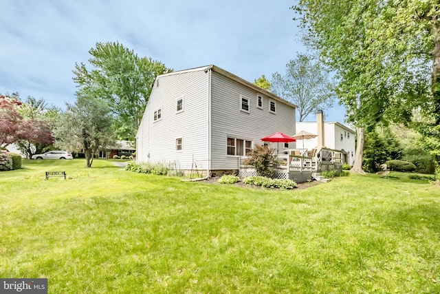 back of property featuring a wooden deck and a lawn
