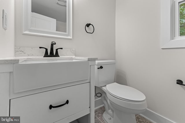 half bathroom featuring vanity, baseboards, and toilet