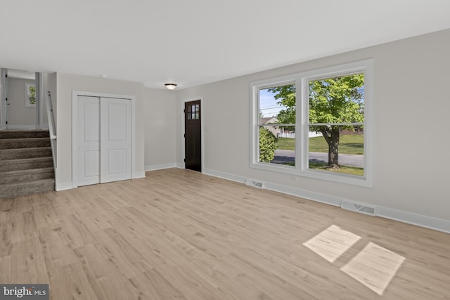 unfurnished living room featuring plenty of natural light, light wood-type flooring, and baseboards
