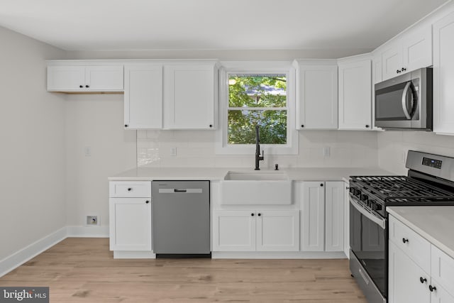 kitchen with stainless steel appliances, a sink, white cabinetry, and decorative backsplash