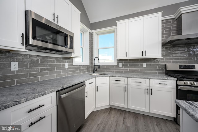 1308 E Bay Ave, Manahawkin, NJ 08050 - kitchen featuring stainless steel appliances, a sink, wall chimney range hood, lofted ceiling, and white cabinetry