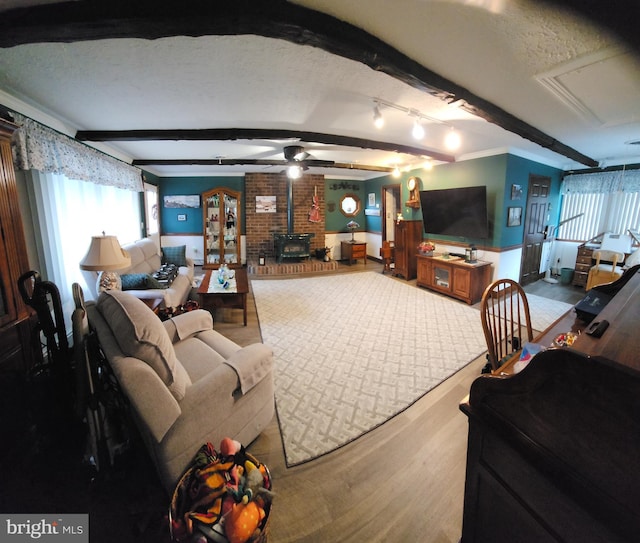 214 Alden Ave, Morrisville, PA 19067 - living room featuring a wood stove, beam ceiling, wood finished floors, ceiling fan, and plenty of natural light