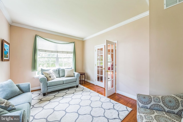 living area with ornamental molding, baseboards, and wood finished floors