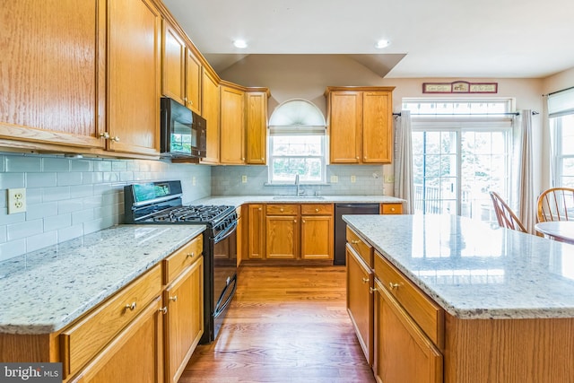 kitchen featuring black appliances, a sink, light wood finished floors, plenty of natural light, and recessed lighting