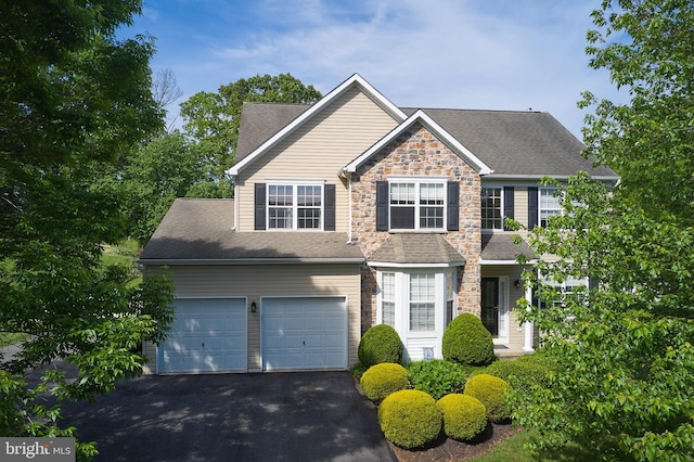 traditional home with stone siding, asphalt driveway, and roof with shingles