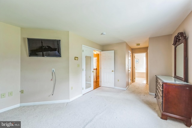 unfurnished bedroom featuring light colored carpet, baseboards, and ensuite bath