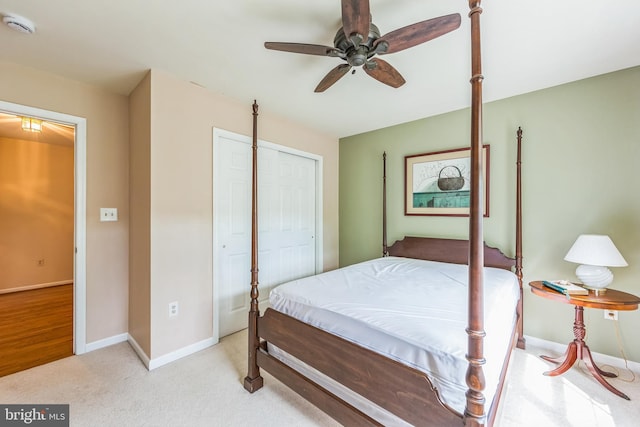 bedroom with light colored carpet, baseboards, a closet, and a ceiling fan