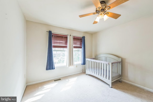 bedroom featuring carpet floors, baseboards, a nursery area, and a ceiling fan