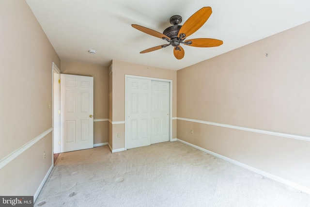 unfurnished bedroom featuring carpet, a closet, baseboards, and a ceiling fan