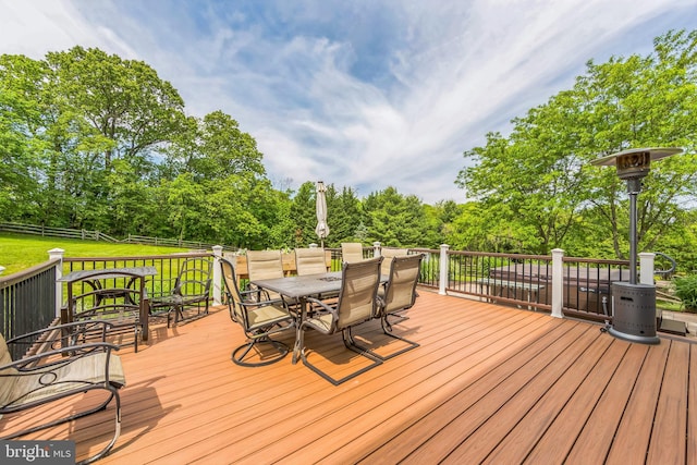 wooden terrace with outdoor dining space and view of wooded area