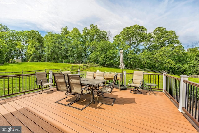 deck with outdoor dining area and view of wooded area