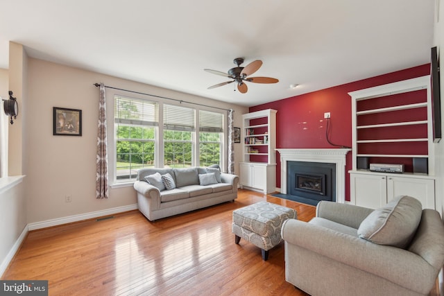 living room with a fireplace with flush hearth, ceiling fan, wood finished floors, and baseboards