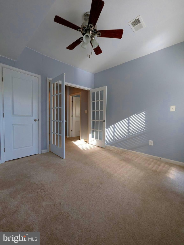 carpeted spare room with ceiling fan, baseboards, and french doors