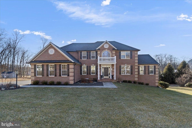 colonial inspired home featuring brick siding and a front yard