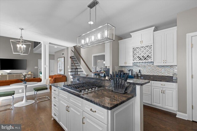 kitchen with stainless steel gas cooktop, a chandelier, open floor plan, backsplash, and a center island