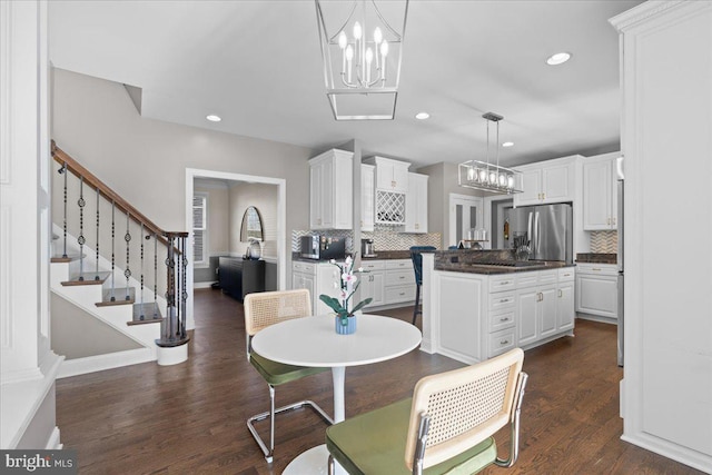 dining area featuring a chandelier, recessed lighting, dark wood finished floors, and stairs