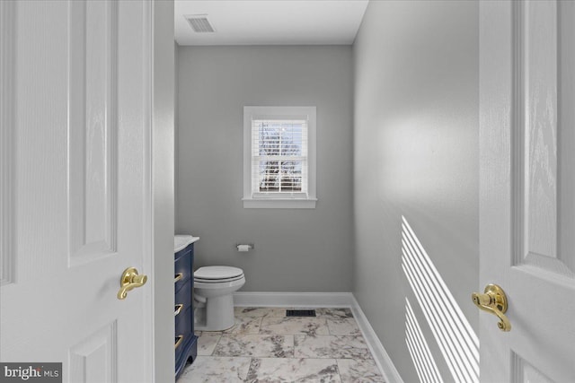 bathroom with marble look tile flooring, vanity, toilet, and baseboards
