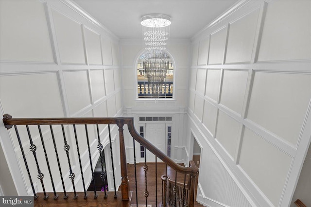 staircase featuring a decorative wall, a chandelier, and crown molding