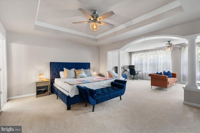 carpeted bedroom with decorative columns, ornamental molding, a raised ceiling, arched walkways, and a ceiling fan
