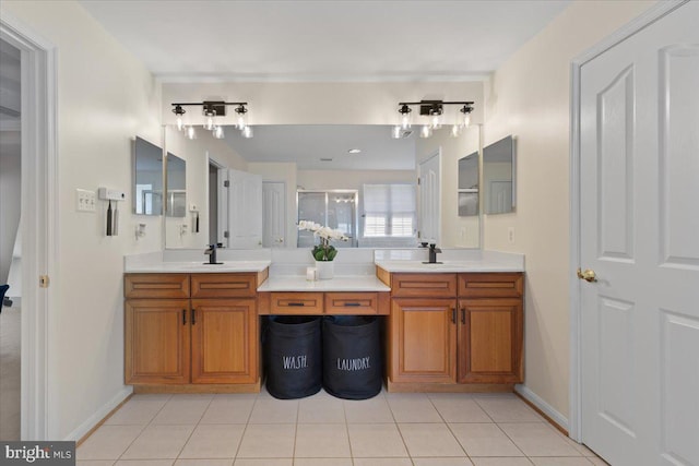 bathroom with double vanity, tile patterned floors, an enclosed shower, and baseboards