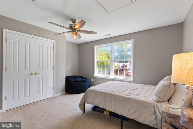carpeted bedroom featuring a closet, attic access, baseboards, and ceiling fan