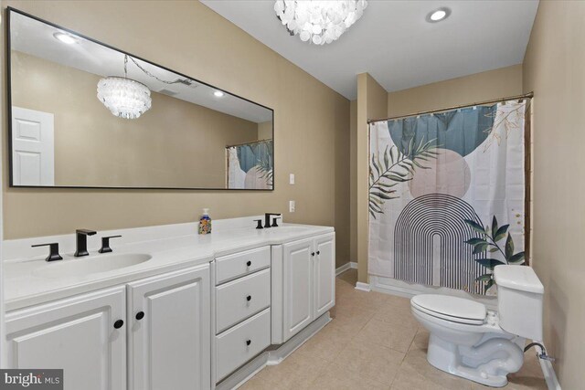 bathroom with a chandelier, tile patterned flooring, toilet, and double vanity