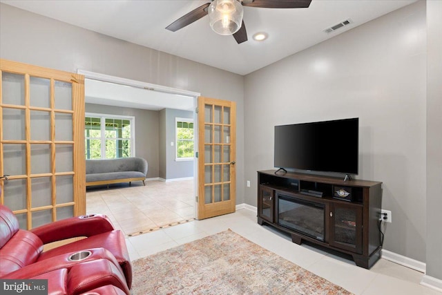 living room with tile patterned floors, ceiling fan, and baseboards