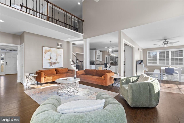 living room featuring wood finished floors, stairs, a ceiling fan, baseboards, and a high ceiling