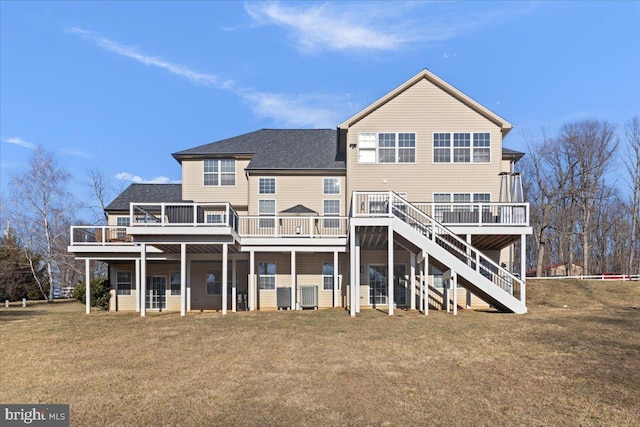 rear view of house featuring stairway, a deck, a shingled roof, and a lawn