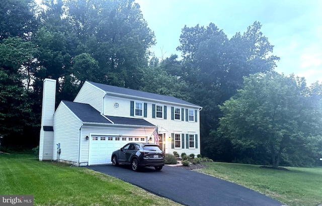 16068 Hayes Ln, Woodbridge, VA 22191 - view of front facade with a chimney, asphalt driveway, a front lawn, and an attached garage