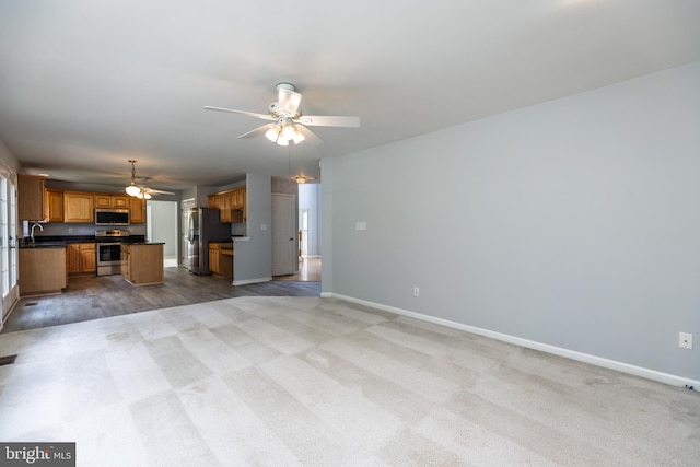 460 Preakness Run, Newark, DE 19702 - unfurnished living room featuring ceiling fan, baseboards, light colored carpet, a sink, and healthy amount of natural light