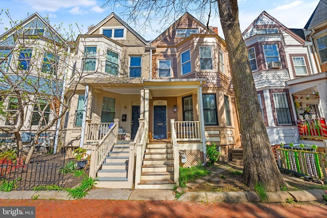 townhome / multi-family property featuring a porch, fence, and stone siding