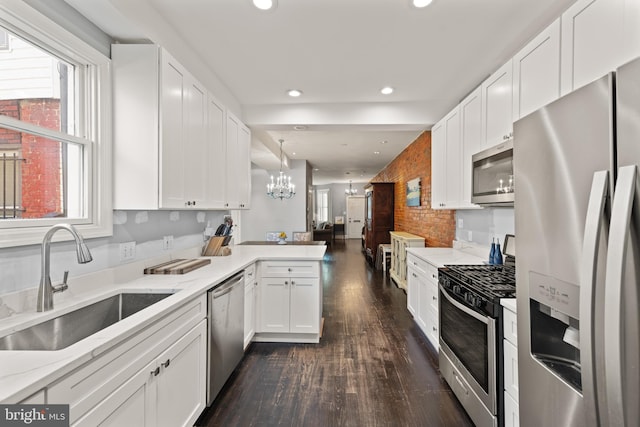 kitchen with appliances with stainless steel finishes, a sink, a chandelier, a peninsula, and recessed lighting