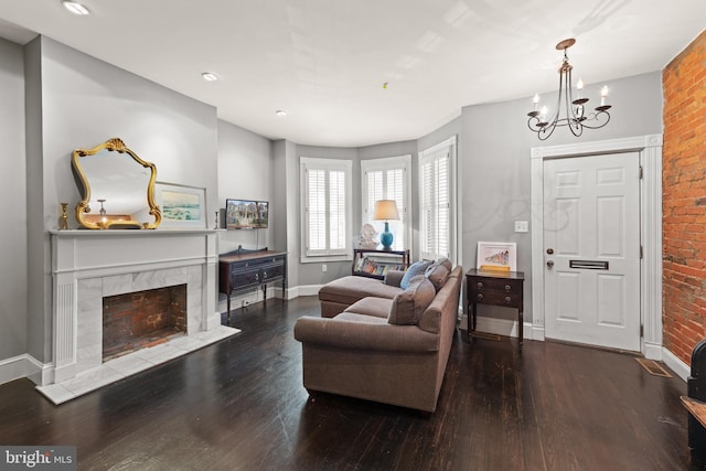 living area featuring a chandelier, brick wall, wood finished floors, a high end fireplace, and baseboards