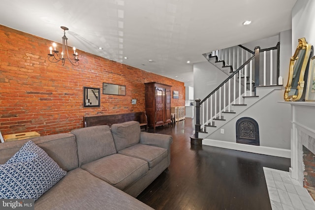 living area featuring stairs, wood finished floors, a chandelier, brick wall, and baseboards