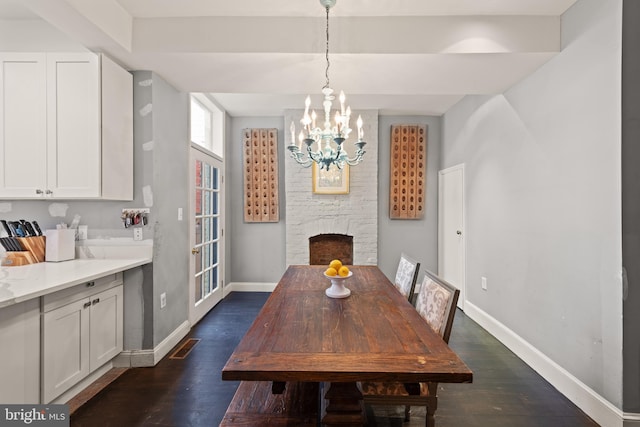 dining space with baseboards, dark wood-type flooring, a chandelier, and a stone fireplace