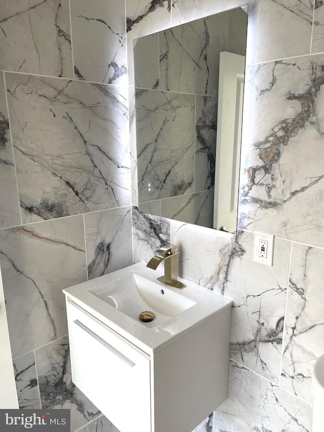bathroom with tile walls, vanity, stone wall, and marble tiled floors