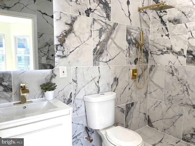full bath with tile walls, vanity, toilet, and a marble finish shower