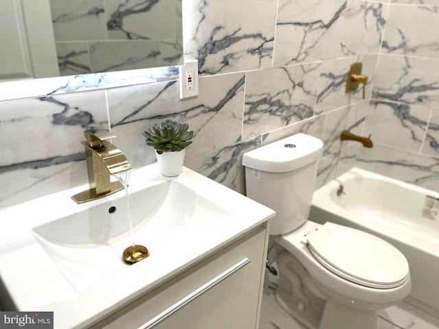 bathroom with marble finish flooring, vanity, toilet, tile walls, and a tub to relax in