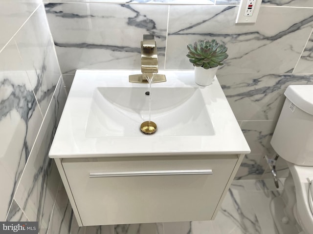 bathroom featuring tile walls, toilet, vanity, and marble finish floors