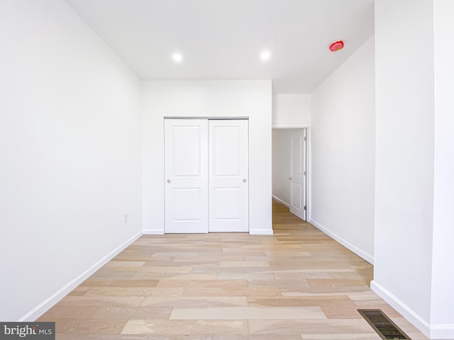 unfurnished bedroom with baseboards, recessed lighting, light wood-type flooring, and a closet