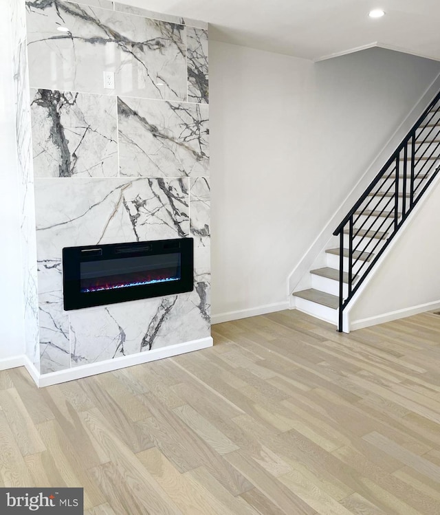unfurnished living room with wood finished floors, baseboards, stairway, a fireplace, and recessed lighting
