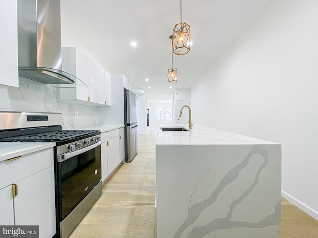 kitchen with stainless steel appliances, a sink, wall chimney exhaust hood, white cabinetry, and a kitchen island with sink