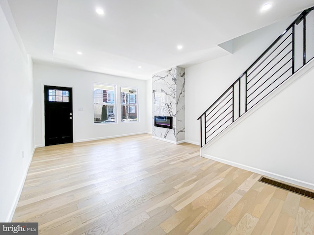 unfurnished living room with stairway, light wood-style flooring, recessed lighting, and baseboards