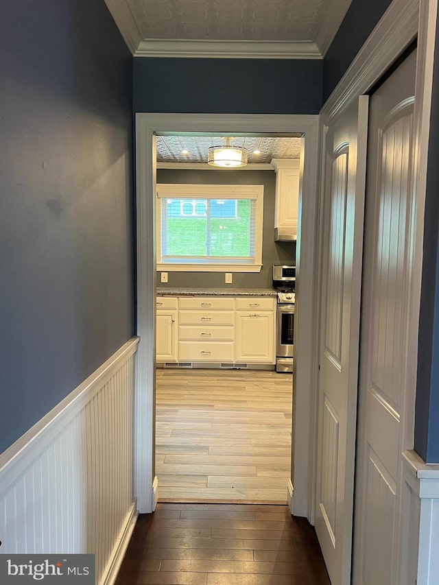 hallway with ornamental molding and light wood-type flooring